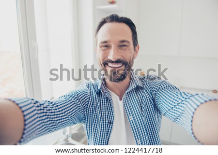 Funky attractive handsome good-wearing stylish trendy glad brunet hair man take selfie stand inside bright light white room hold camera two hands