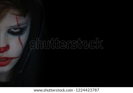 young boy with scary clown makeup     