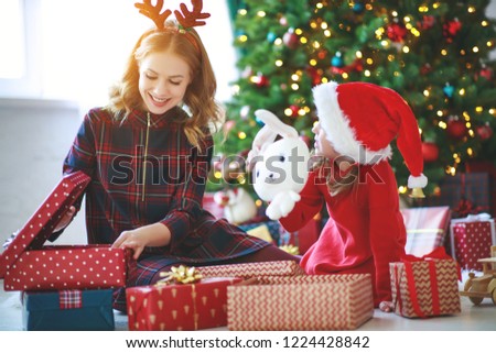 happy family mother and child daughter  open presents on Christmas morning
