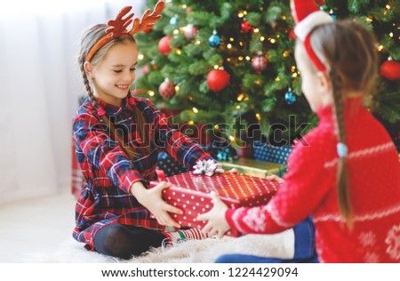 happy children girls with christmas gifts near christmas tree in morning
