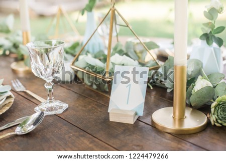 bohemian blue wedding table number on a wooden table, eucalyptus and gold decoration, watercolor style, bokeh background Royalty-Free Stock Photo #1224479266