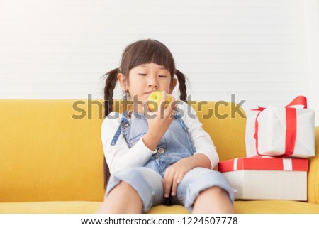 Happy Holidays! Cheerful cute childrens girls eat apple near present gift at white living room.
