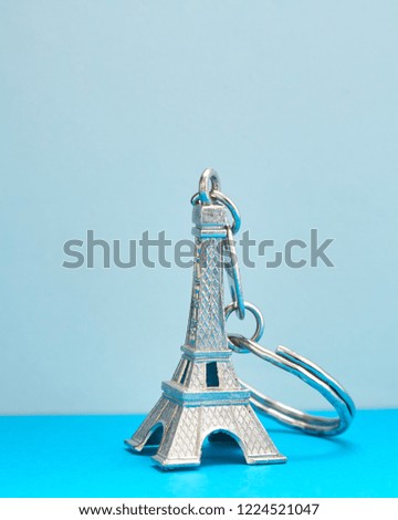 Eiffel tower model key chain on Composition Blue paper copy space ,travel icon concept