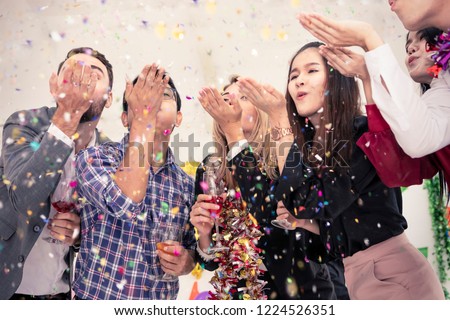 Group of celebrate blowing colorful confetti and looking happy on white background.Group of friend having fun,drink champagne and alcohol cocktails in holiday.