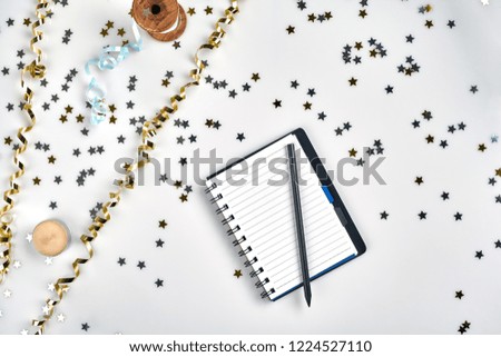Flat Lay Christmas or Party Background with colored ribbons, decorations, confetti, and wrapping paper. Notepad for Text in Middle.