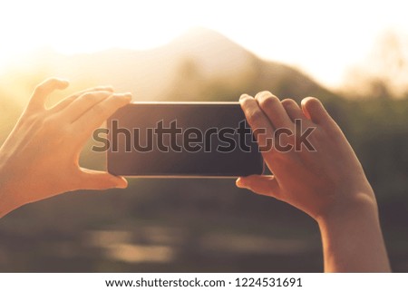 Woman hand take a photo from smartphone camera to beautiful nature view background.