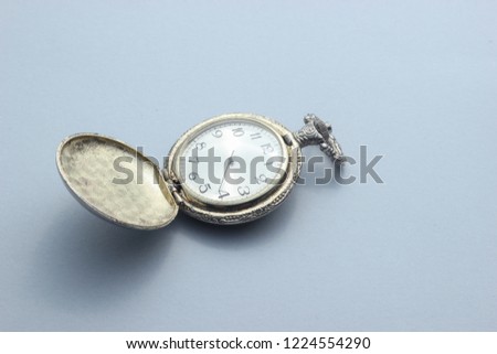 Old pocket watch close-up on gray background.
