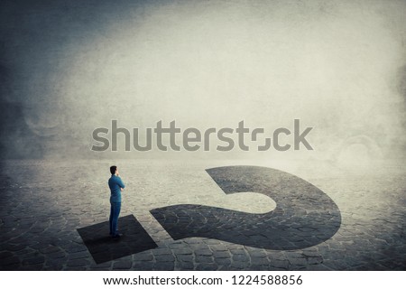 Business questions and decision making as a thoughtful young man standing on a huge interrogation mark shadow looking to light. Unknown future and opportunity. Royalty-Free Stock Photo #1224588856