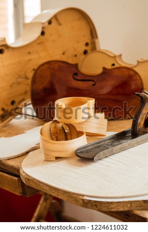 Wood shaving curls and carpentry plane used for making Cello or, violoncello, with semi assembled cello in background