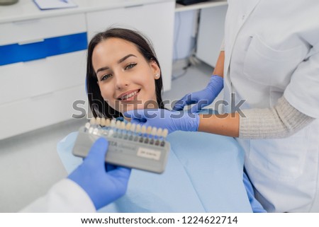 Dentist examining whiteness of patient teeth