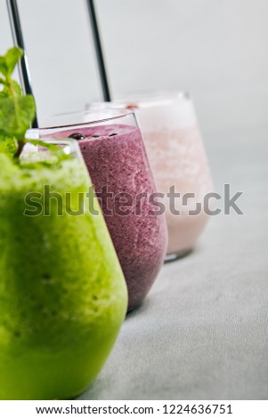 Close-up picture of glass of smoothy with juicy bilberry banana and tasty yogurt. Purple cooling beverage. Summer drink concept. Isolated on grey background