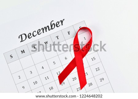 World AIDS Day concept, red ribbon circle the date 1 December on white calendar background with copy space for text, an international day dedicated to raising awareness of the AIDS