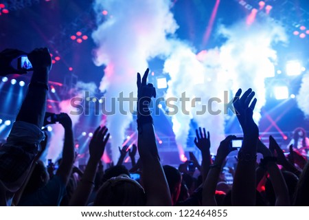 Picture of rock concert, music festival, New Year eve celebration, party in nightclub, dance floor, disco club, many people standing with raised hands up and clapping, happiness and night life concept Royalty-Free Stock Photo #122464855
