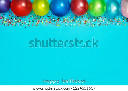 Multicolor party or birthday background on blue with a frame of colorful party balloons, streamers, confetti and candy around central copy space. Happy Birthday 