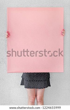 Girl holding blank pink canvas on a stretcher. 