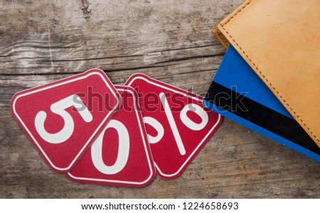 Leather wallet with a percentage discount label on old wooden background top view