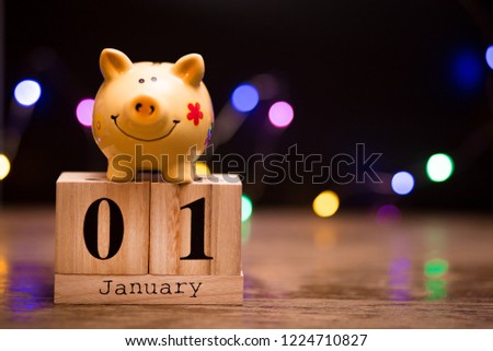 Calendar date of Financial Year start, 1st january with piggy bank on dark background with garland bokeh.
