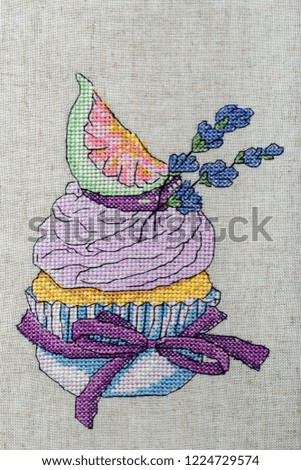 Lavender cake with figs embroidered on gray fabric.