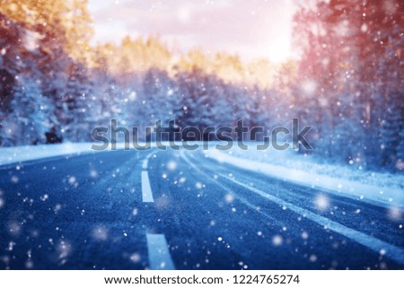 winter road, covered with snow on sunny day. Black icy asphalt