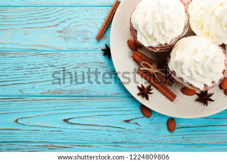Tasty cream cupcakes on blue wooden. Free space for text. Top view.