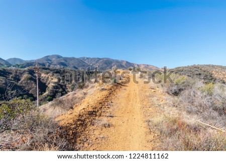 Dirt path or road in forest of Southern California for hiking and biking on sunny fall day