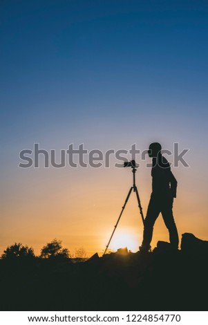 Silhouette of black photographer taking pictures at sunset. Image with copy space.