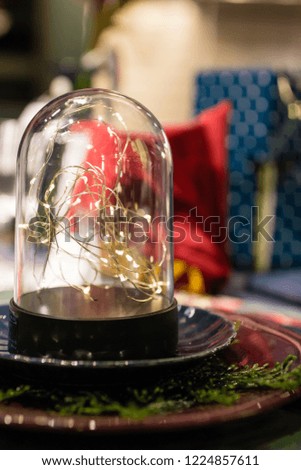 Christmas time and New Year holidays table decoration with Christmas lights on glass sphere. Magic holiday atmosphere in scandinavian style. Shallow depth of field blurry Christmas bokeh background.