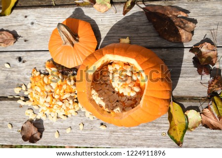 Top view of carved pumpkin making jack-o-lantern on rustic wooden table showing seeds and fruit
