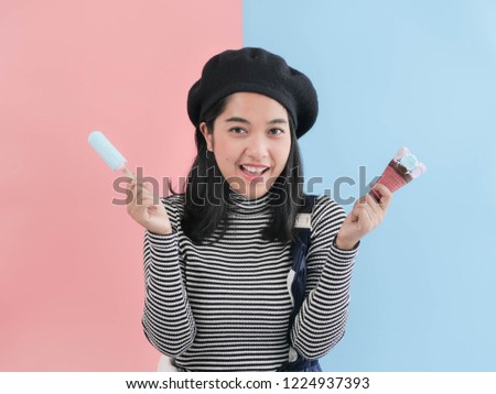 Happy Asian woman eating blue ice cream stick with color background.