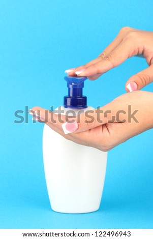woman squeezing lotion on her hand, on blue background close-up