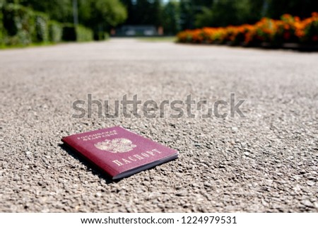 Russian passport on the pedestrian pathway, the background of green bushes and trees