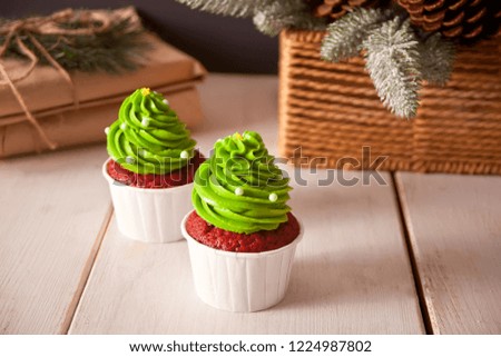 Bright red velvet cupcakes in the form of Christmas trees on a white wooden background