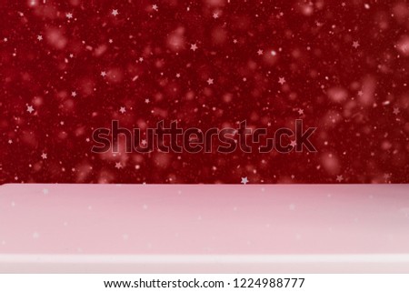 abstract dark red starry wall with snowflakes and empty white table.