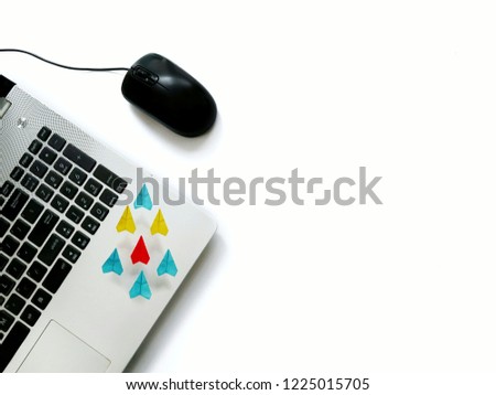 Laptop and mouse on white background and decorated by flying colorful paper planes for information system concept.
