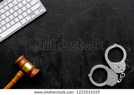 Arrest of a hacker for cyber fraud concept. Handcuff near keyboard and judge gavel on black background top view copy space