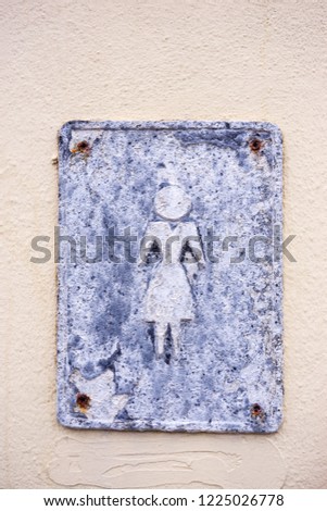 Old metal plate with sign â€œFor womenâ€ on a stucco wall. Close up.