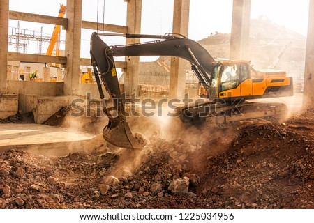 The excavator is digging in the building of the construction site. 
