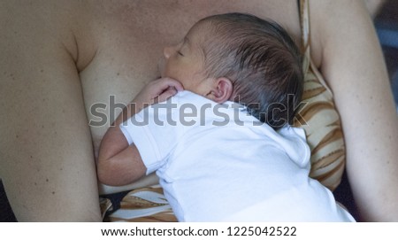 Realxed newborn baby sleeping on mother's breast.
