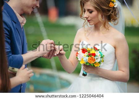 The groom puts the ring on the bride