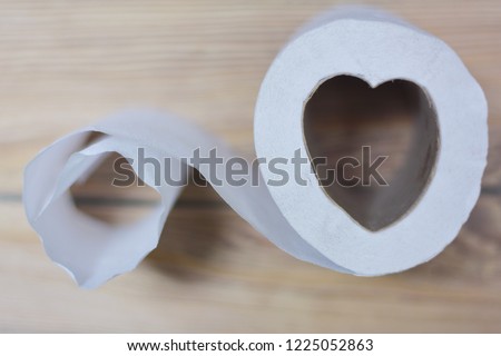Toilet paper in the form of heart. Wooden background.
