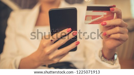 Save as much money as you can. Smiling young woman paying online with her credit card. Focus is on hands. Close up.