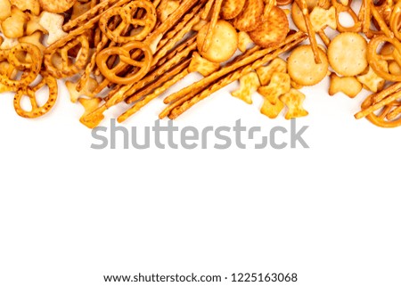 A variety of salty crackers, sticks, pretzels, and goldfishes, shot from the top on a white background with copy space. Party snacks mix with copy space