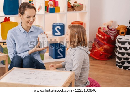 Smiling therapist showing picture of ring during meeting with autistic girl