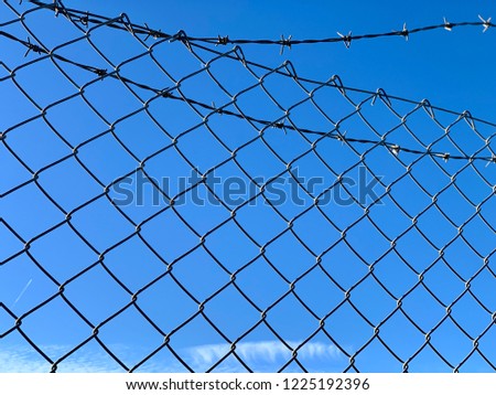Clear winter sky viewed through a security fence