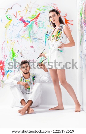 barefoot couple in painted white clothes with drawing equipment