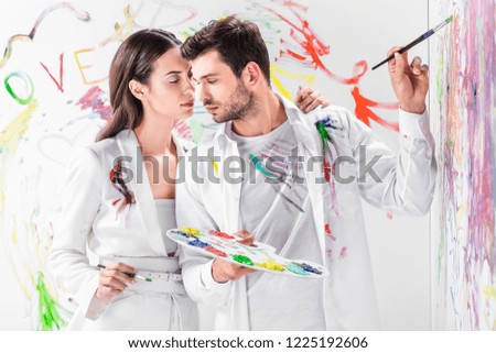 close up of tender couple in total white drawing with paints on wall