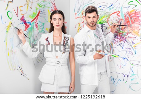 fashion shoot of couple in total white drawing with paints on wall