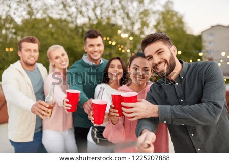 leisure and people concept - happy friends with drinks taking selfie at rooftop party in summer
