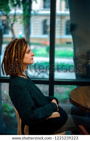 closeup redhead woman with dreadlocks sitting in a cafe