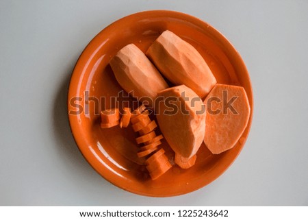 Mixed Vegetables Raw Sliced Sweet Potatoes Batat and Carrot on an Orange Plate